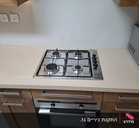 כיריים ותנור במטבח מודרני עם ארונות עץ.